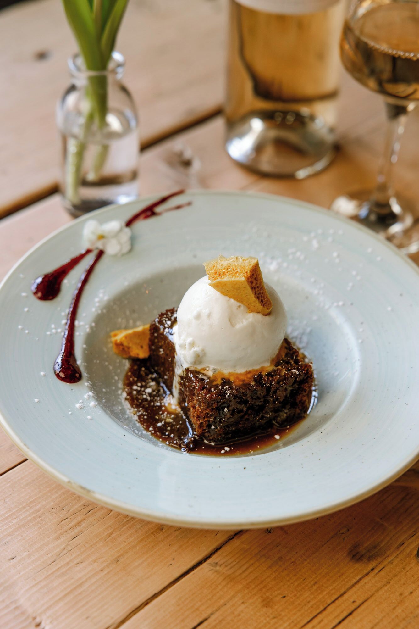 A dessert plate with a scoop of ice cream on top of a cake, accompanied by a drizzle of sauce and a piece of cake on the side.