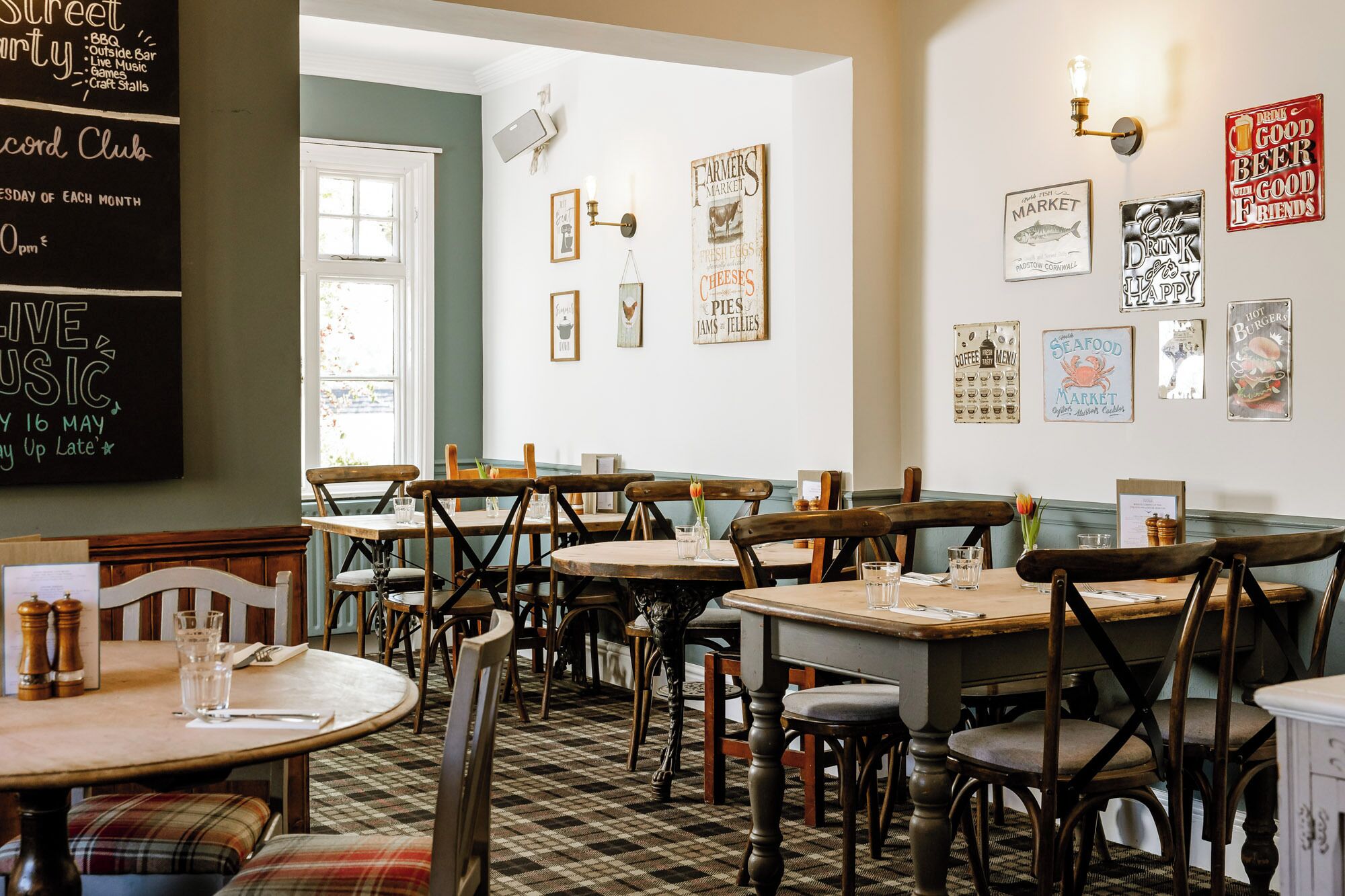 A restaurant interior with wooden tables and chairs, a chalkboard menu, and various wall decorations.
