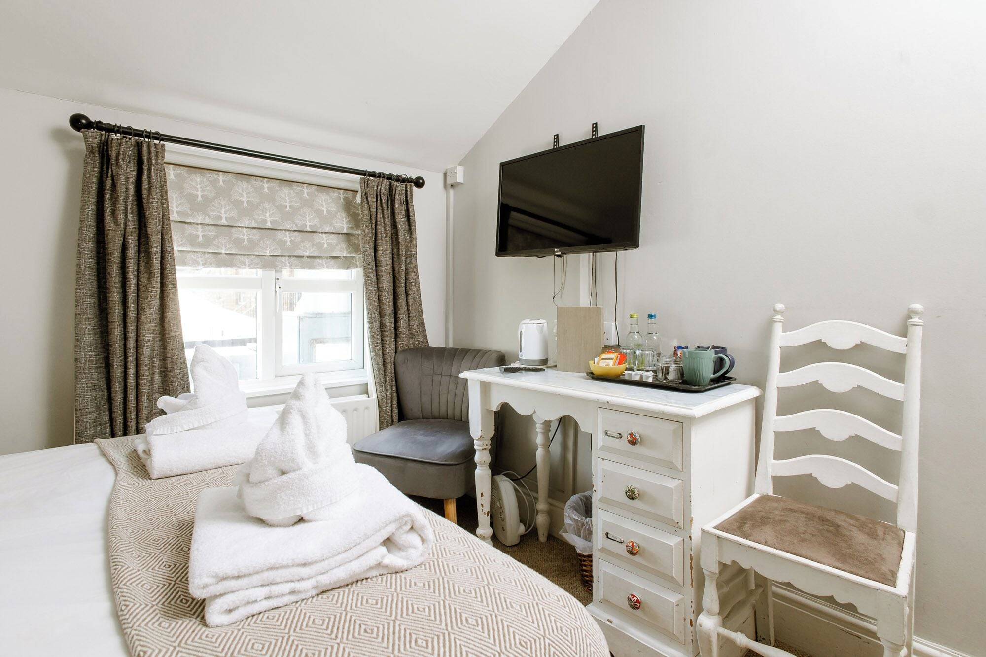 Habitación de hotel con cama, escritorio, televisor de pantalla plana, silla y cómoda.