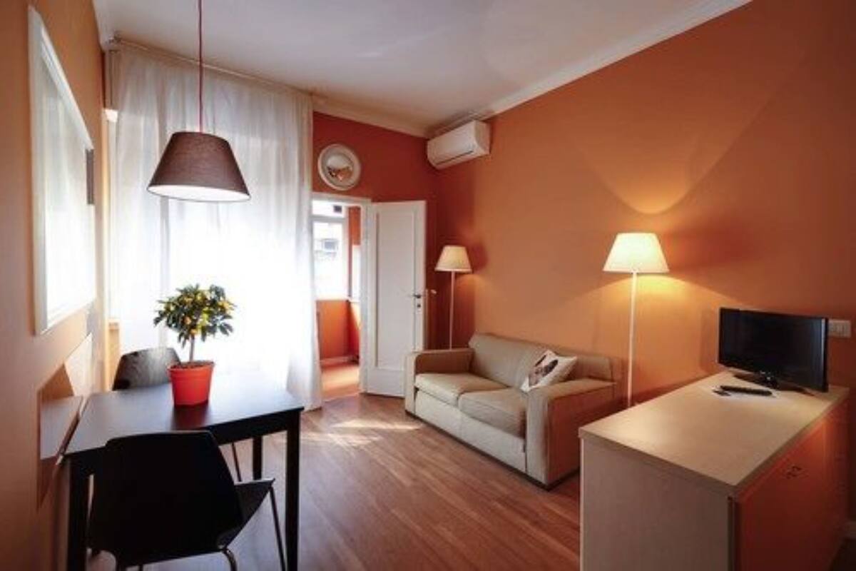 Un espace de vie compact comprenant un coin repas, un canapé, un téléviseur et une lampe.