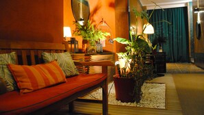 Una habitación acogedora con un banco de madera, un sofá rojo, una jaula de pájaros y una planta en maceta.