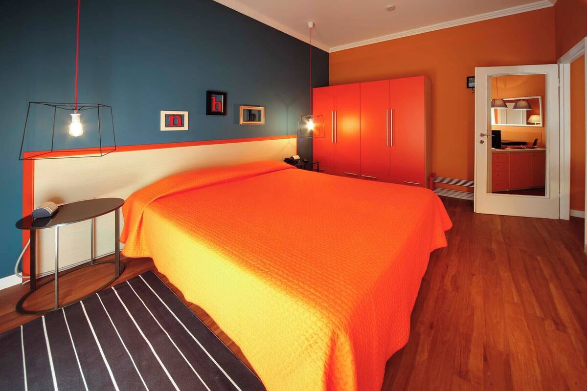 Une chambre à coucher avec un grand lit, une table de chevet, une armoire et un miroir.