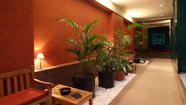 A hallway with a wooden bench, a table with a lamp, and potted plants. - Residence Pian Della Nave (Milan)