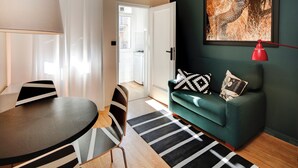 Una sala de estar moderna con un sofá verde, alfombra a rayas negras y blancas y un cuadro de un leopardo en la pared.