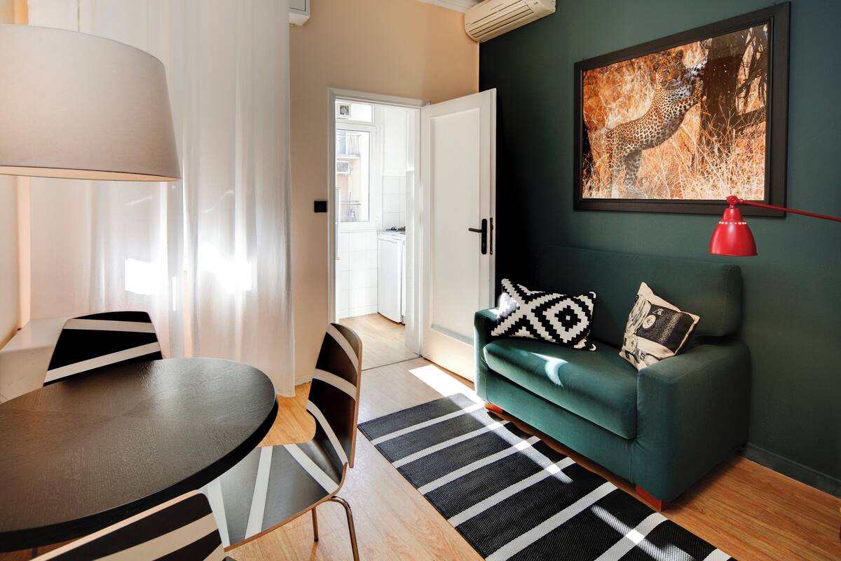 Un salon moderne avec un canapé vert, un tapis à rayures noires et blanches et un tableau représentant un léopard accroché au mur.