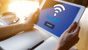 Une personne tenant une tablette sur laquelle est affiché un panneau indiquant « Wi-Fi gratuit ».