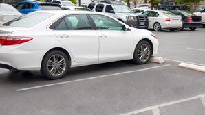 A white sedan parked in a lot with other vehicles. - Traveller's Inn (Summerside)