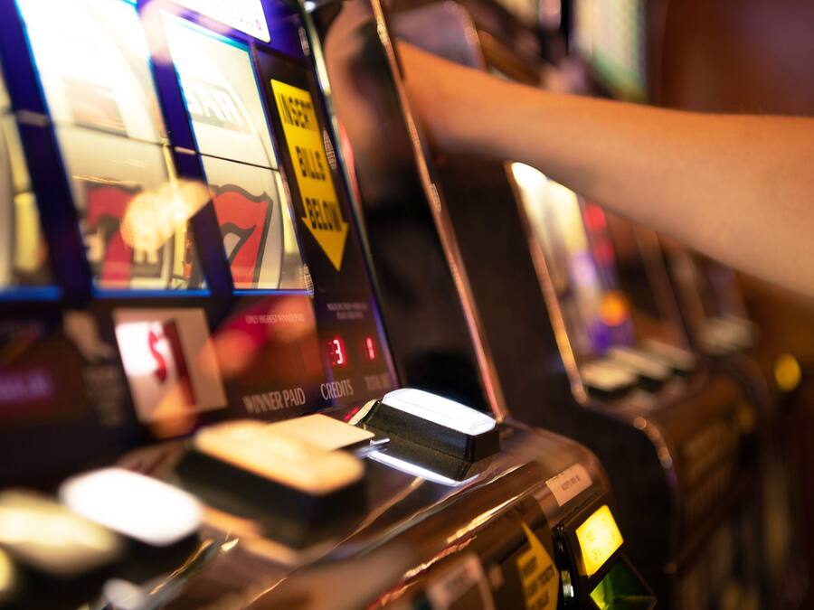 A close-up of a slot machine with a hand reaching for a lever.