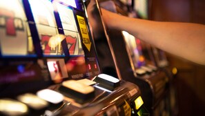 Un gros plan d’une machine à sous, avec une main qui tend la main vers un levier.