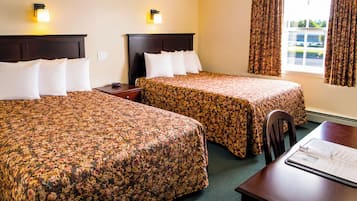 A hotel room with two beds, a desk, and a window with curtains.