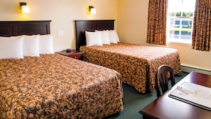 A hotel room with two beds, a desk, and a window with curtains. - Traveller's Inn (Summerside)