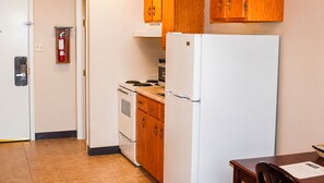 A compact kitchen with a white refrigerator, stove, and wooden cabinets.