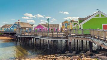 A pier with colorful buildings, wooden railings, and a calm water body.