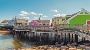 Une jetée bordée de bâtiments aux couleurs vives, de rampes en bois et donnant sur une étendue d’eau calme.