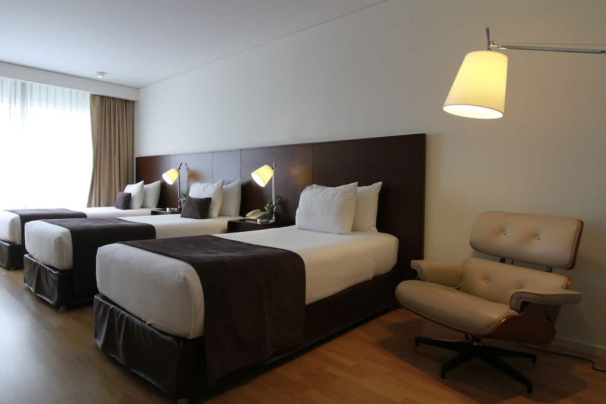 Ein Hotelzimmer mit zwei Betten, einem Schreibtisch, einem Stuhl und einer Lampe.