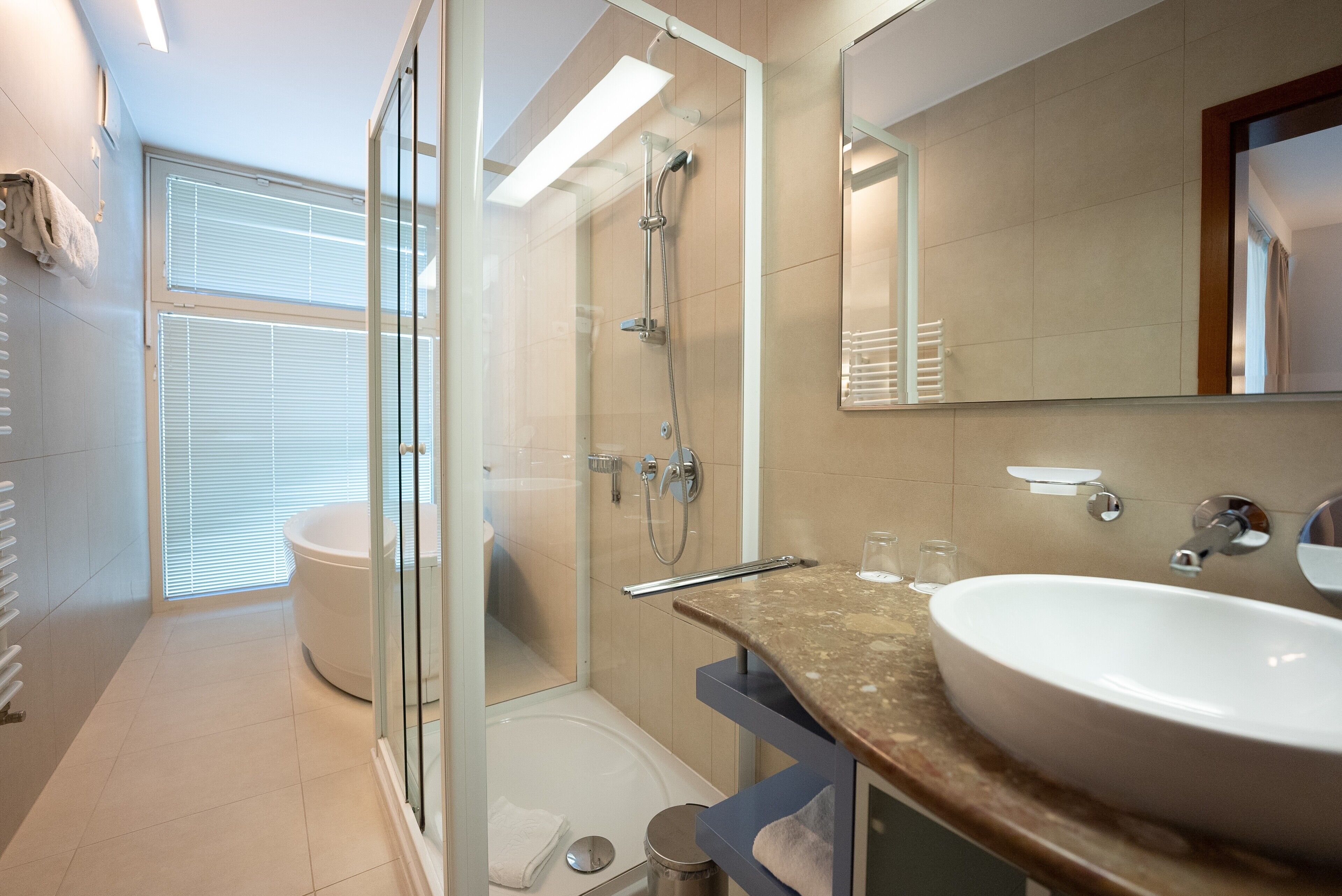 Une salle de bain moderne avec une douche à parois de verre, un grand lavabo et un miroir.