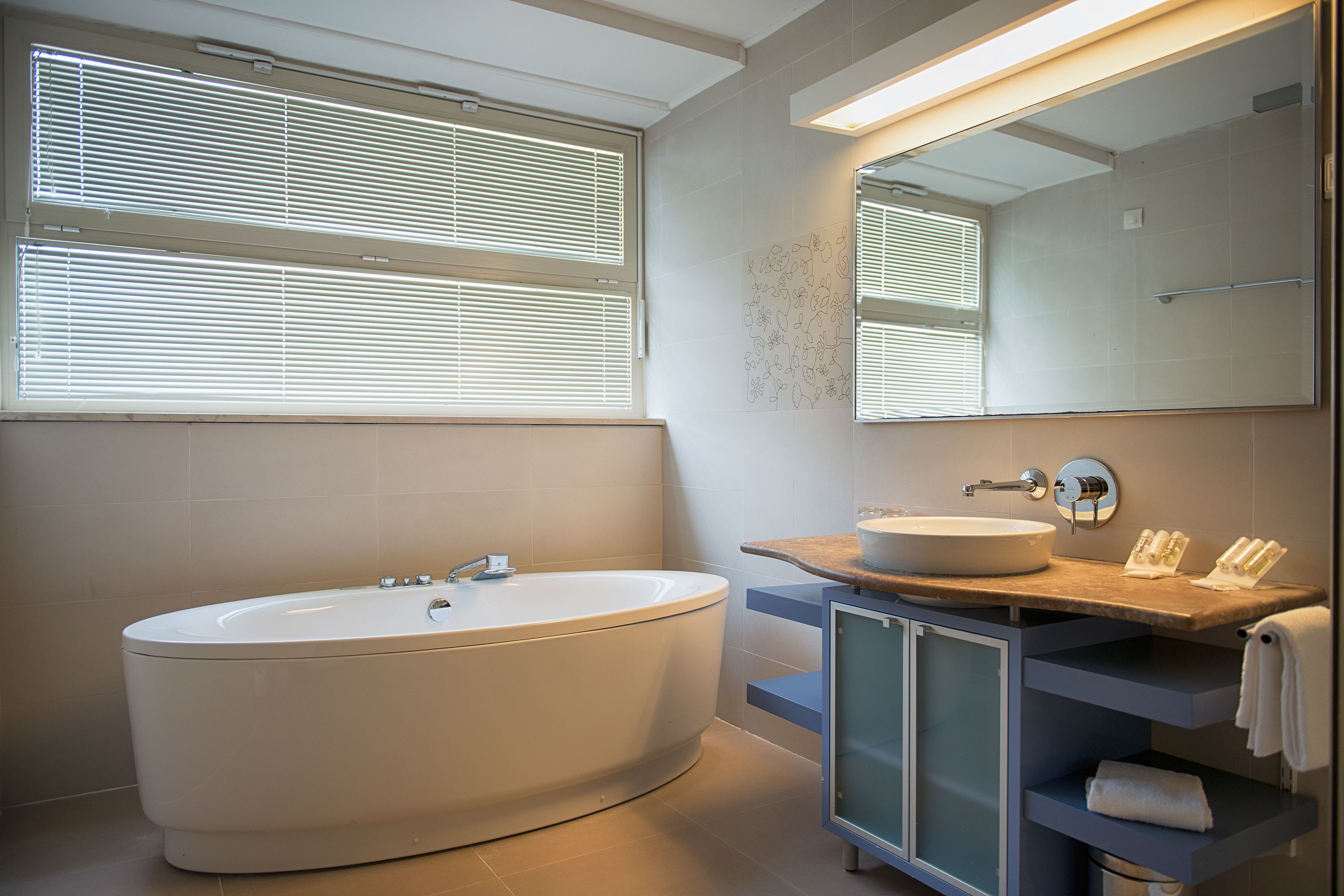 Ein modernes Badezimmer mit einer freistehenden Badewanne, einem Waschbecken mit Ablagefläche und einem großen Spiegel.