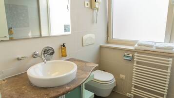 A bathroom with a white sink, a toilet, a hand dryer, and a towel rack.