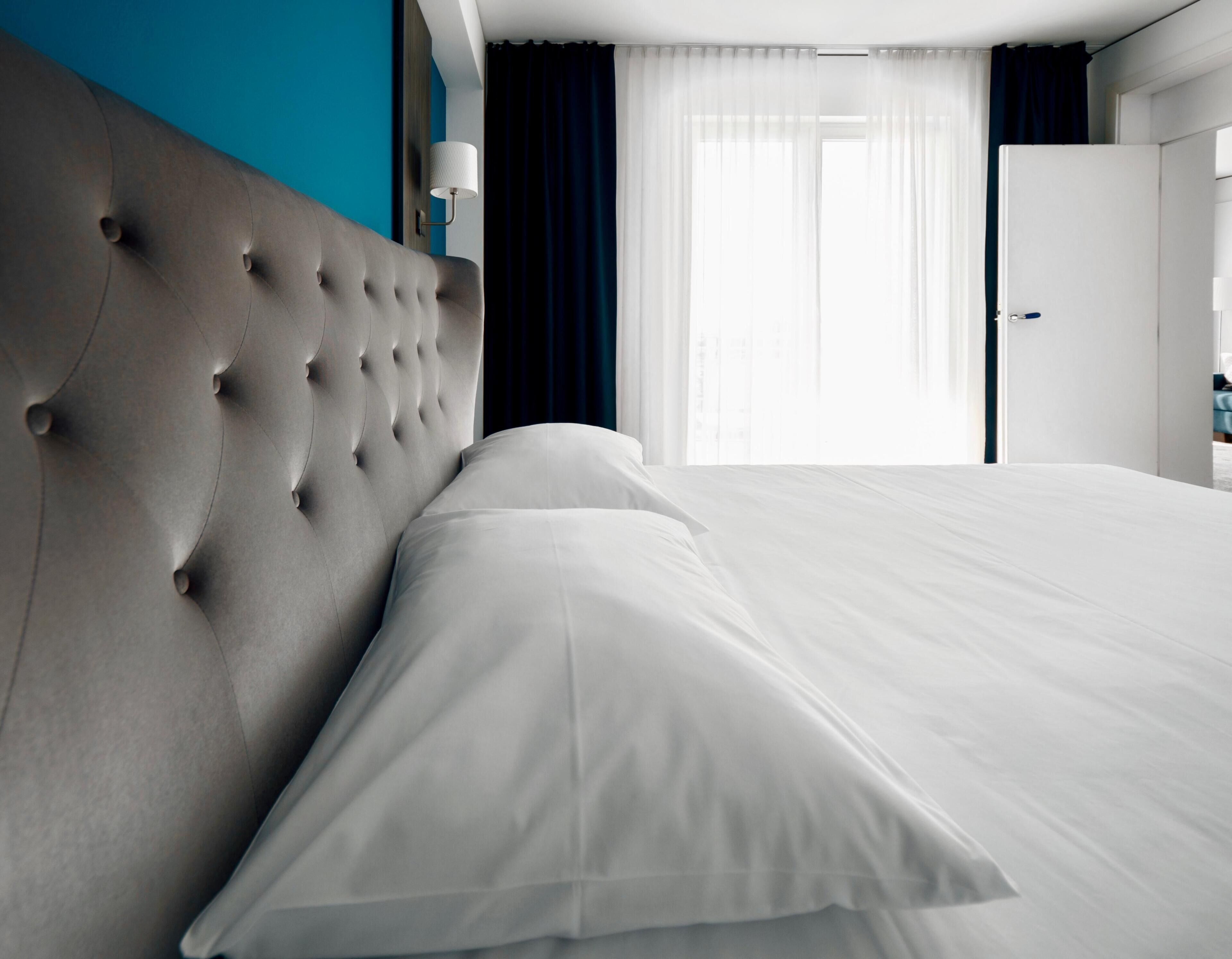Un lit bien fait, avec du linge de lit blanc, dans une chambre d'hôtel.