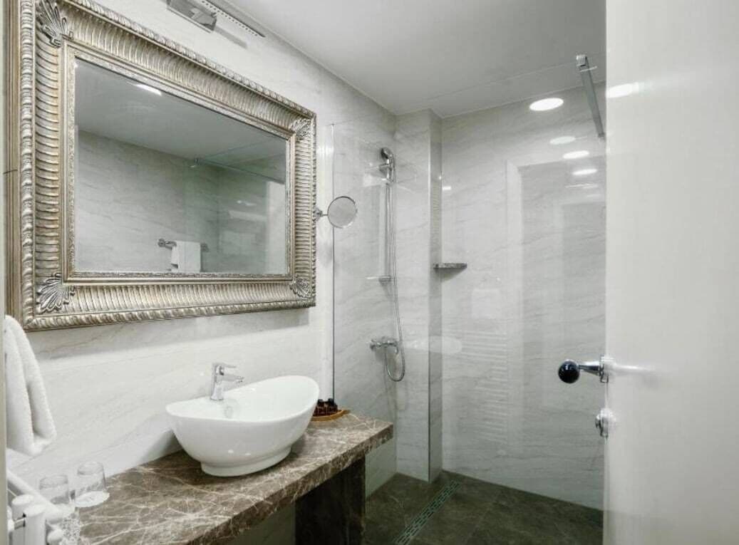 Un baño con un espejo grande, un lavabo y una ducha.