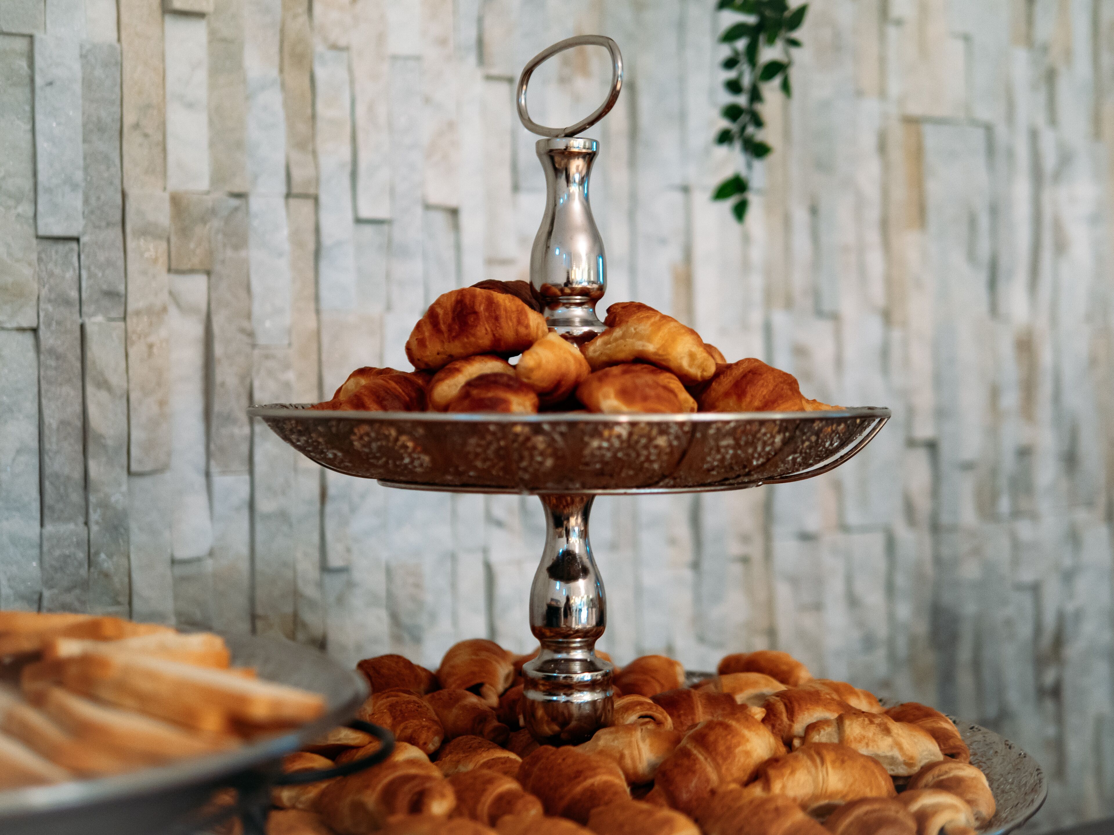 Un plateau à étages rempli de croissants et un autre plateau similaire contenant des petits pains.
