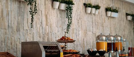 A breakfast buffet with various pastries, a coffee machine, and juice dispensers.