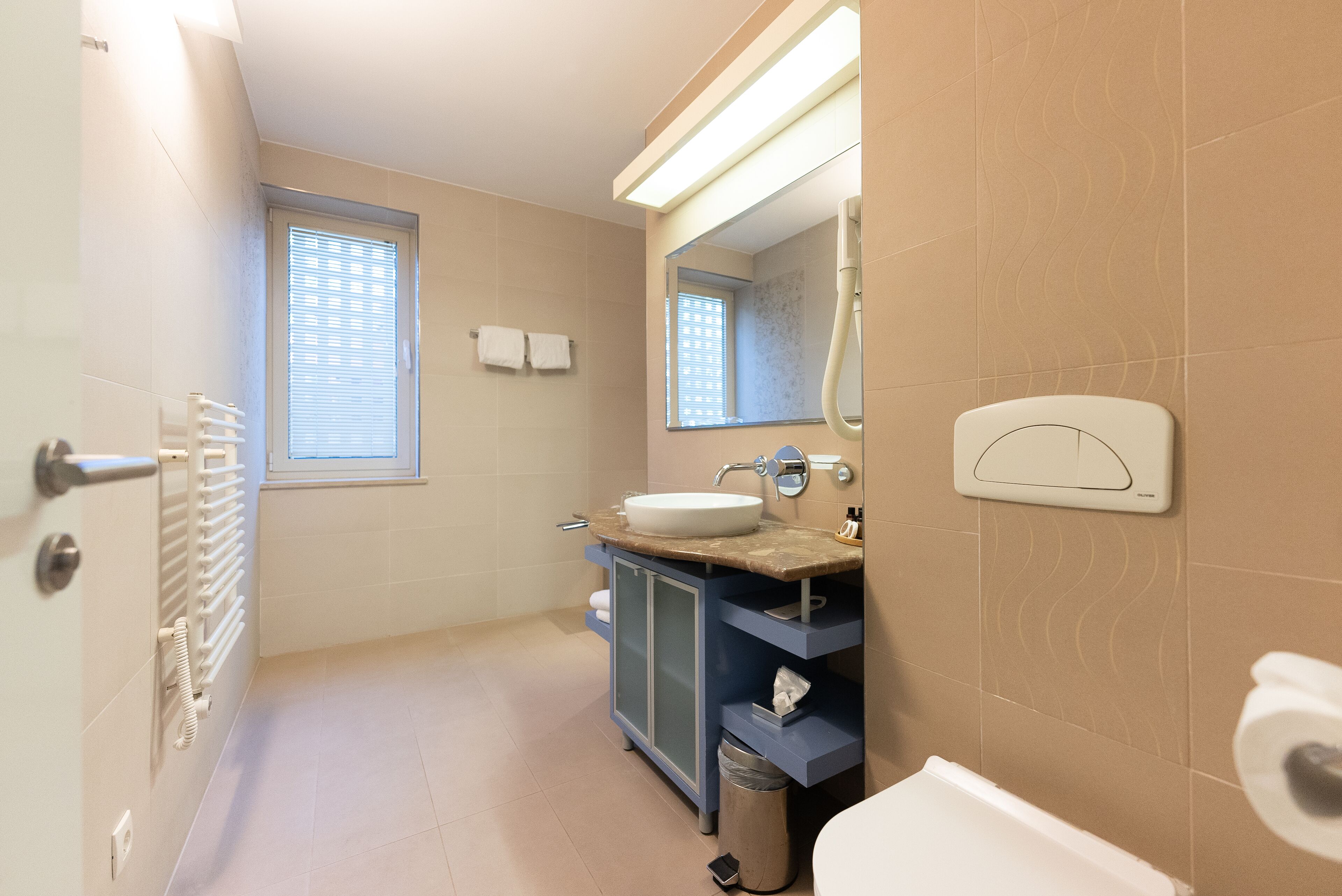 A modern bathroom with a white sink, a mirror, and a towel rack.