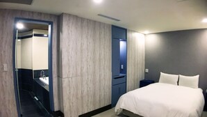 A modern hotel room with a large bed, a built-in wardrobe, a bathroom with a mirror, and a small bedside table. - Spa Spring Hotel (Taipei)