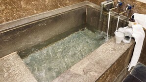 A spa bathtub with clear water, a towel, and two white mugs on the side. - Spa Spring Hotel (Taipei)