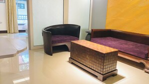 A modern hotel lobby with a seating area featuring a black chair and a brown sofa with a purple cushion. A small wooden table is placed in front of the sofa. - Spa Spring Hotel (Taipei)