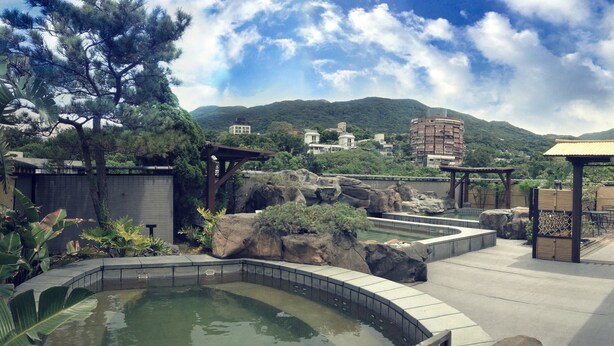A landscaped outdoor area with a pool, seating areas, and a view of a mountain. - Spa Spring Hotel (Taipei)