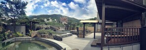 Un espacio exterior ajardinado con piscina, zonas de estar y vistas a la montaña.