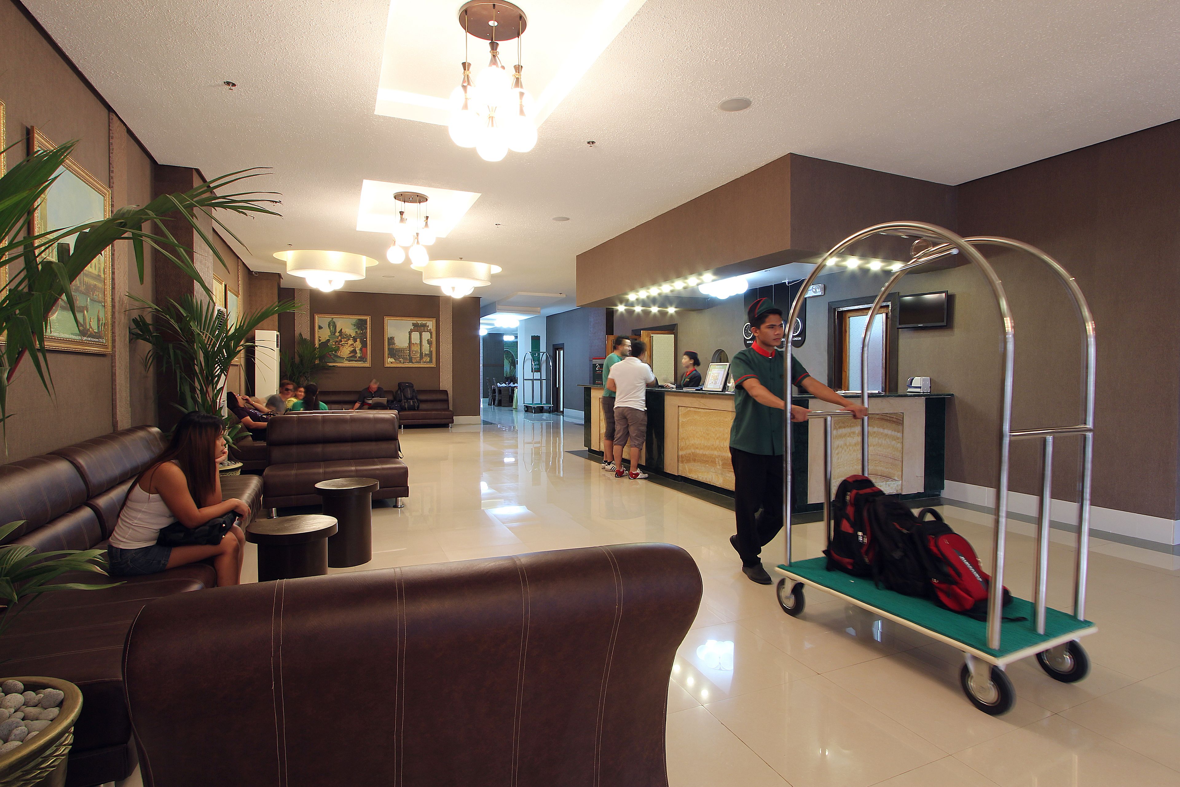 A lobby with leather seating, a reception desk, and a cart with luggage.
