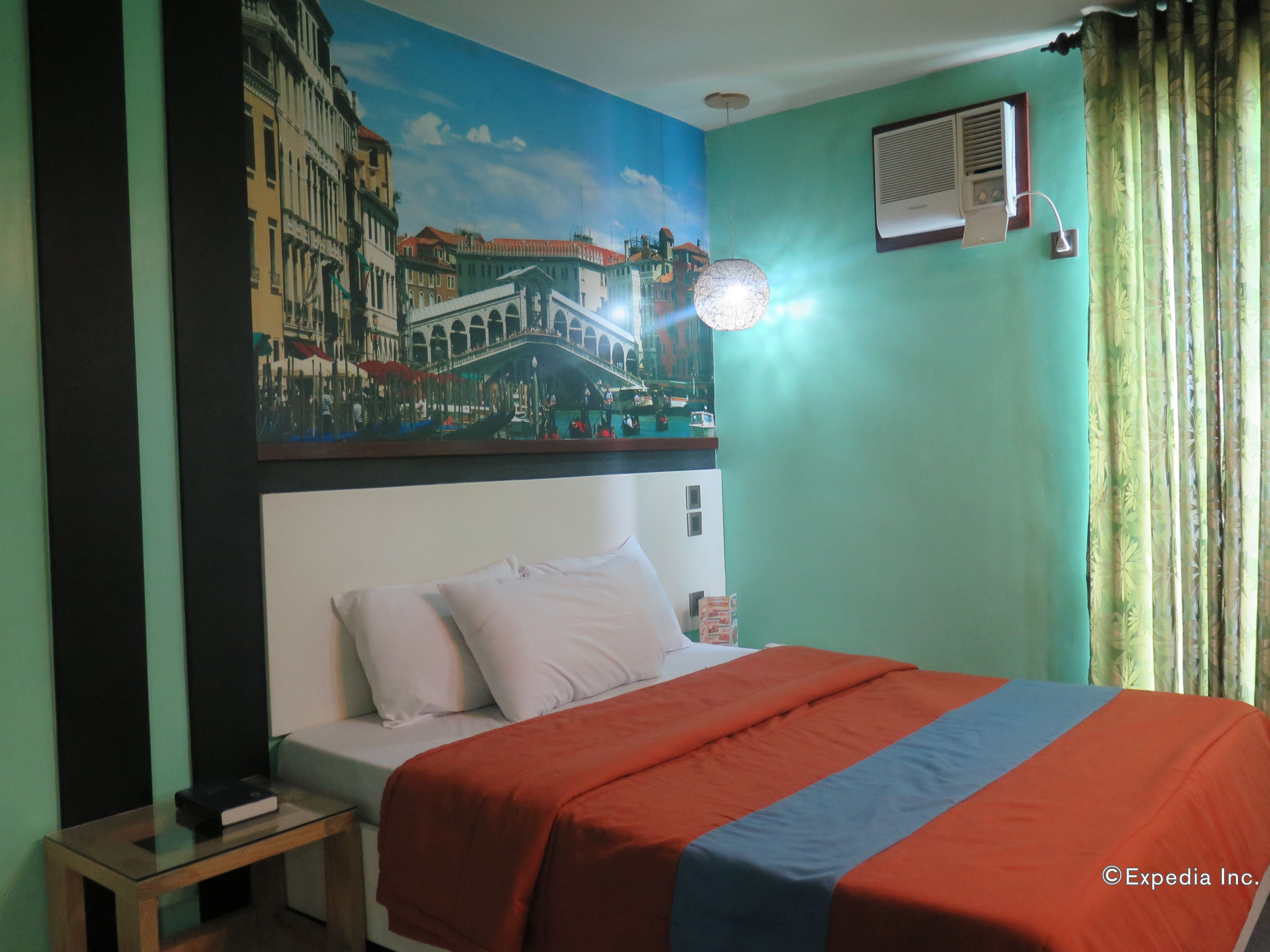 Une chambre d’hôtel comprenant un lit, une table de chevet, un tableau représentant un paysage urbain, un appareil de climatisation et un rideau.