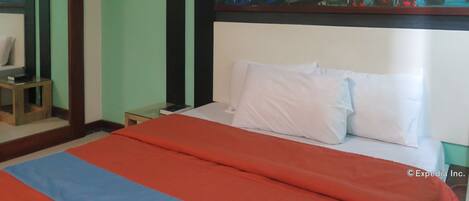 Habitación de hotel con cama, mesita de noche, una pequeña mesa y un cuadro en la pared con una vista urbana.
