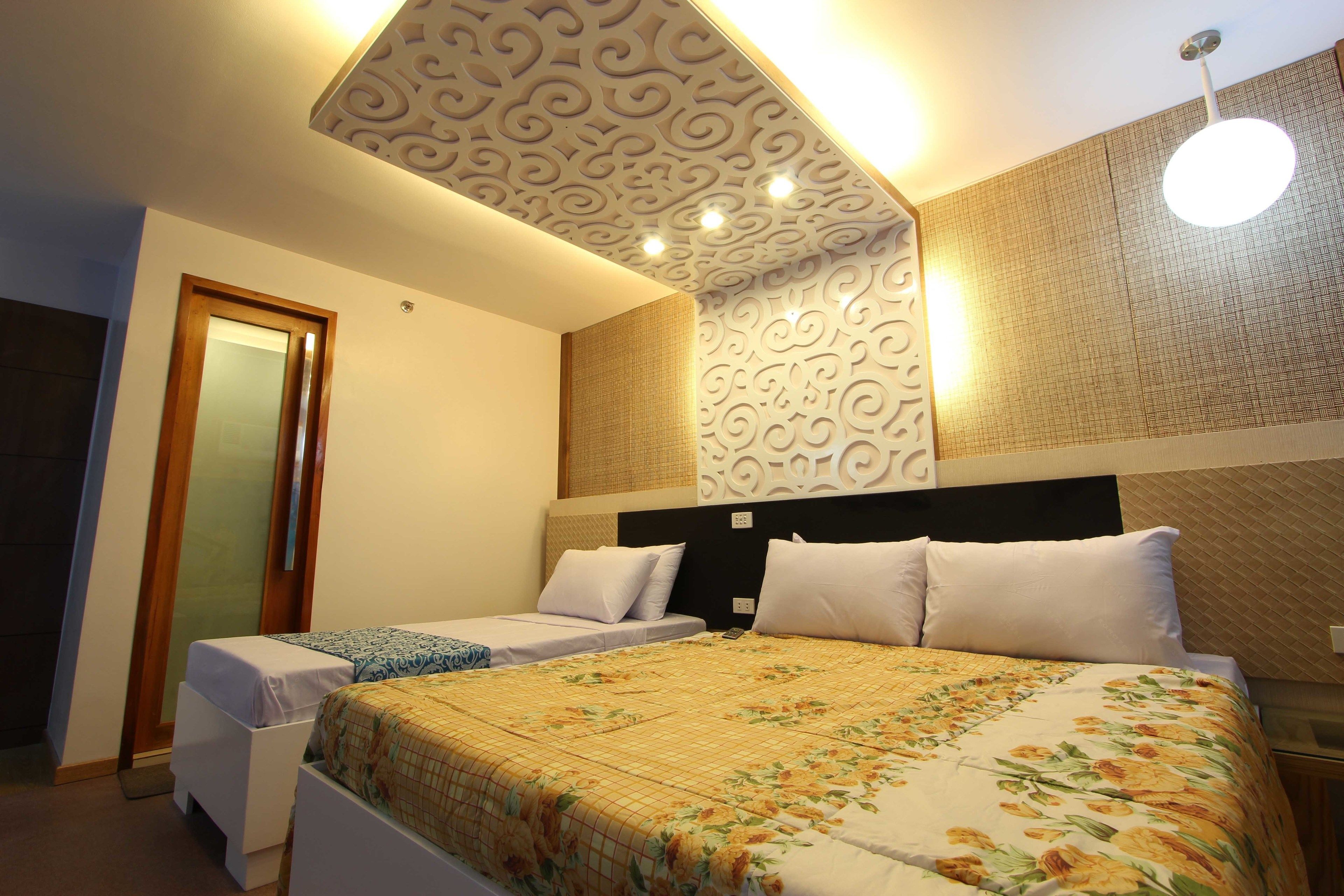 Une chambre d’hôtel avec deux lits, un plafond décoratif et un mur à motifs.