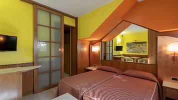 A hotel room with a bed, a desk, a TV, and a large mirror.