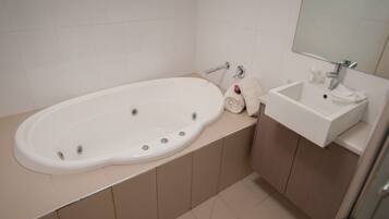 A bathroom with a bathtub, a sink, and a mirror.