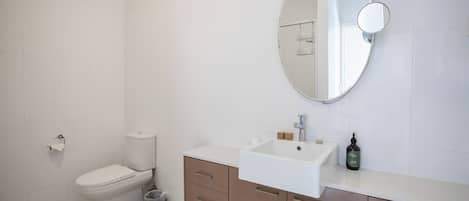 A modern bathroom with a toilet, sink, and mirror.