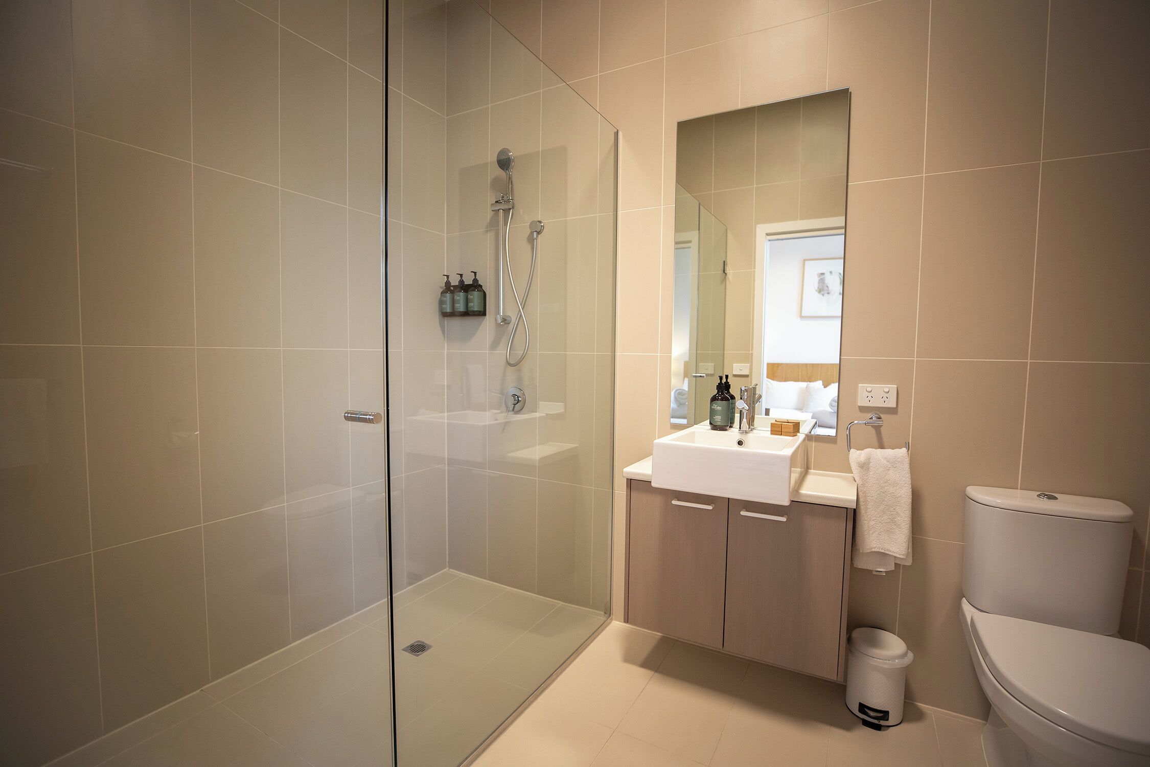 Un baño moderno con ducha de mampara de vidrio, un lavabo blanco y un inodoro.