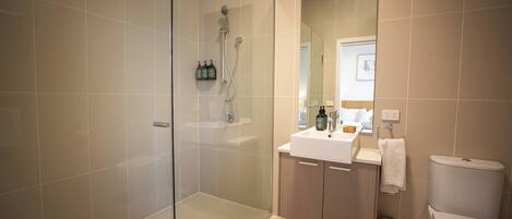 A modern bathroom with a glass-enclosed shower, a white sink, and a toilet.