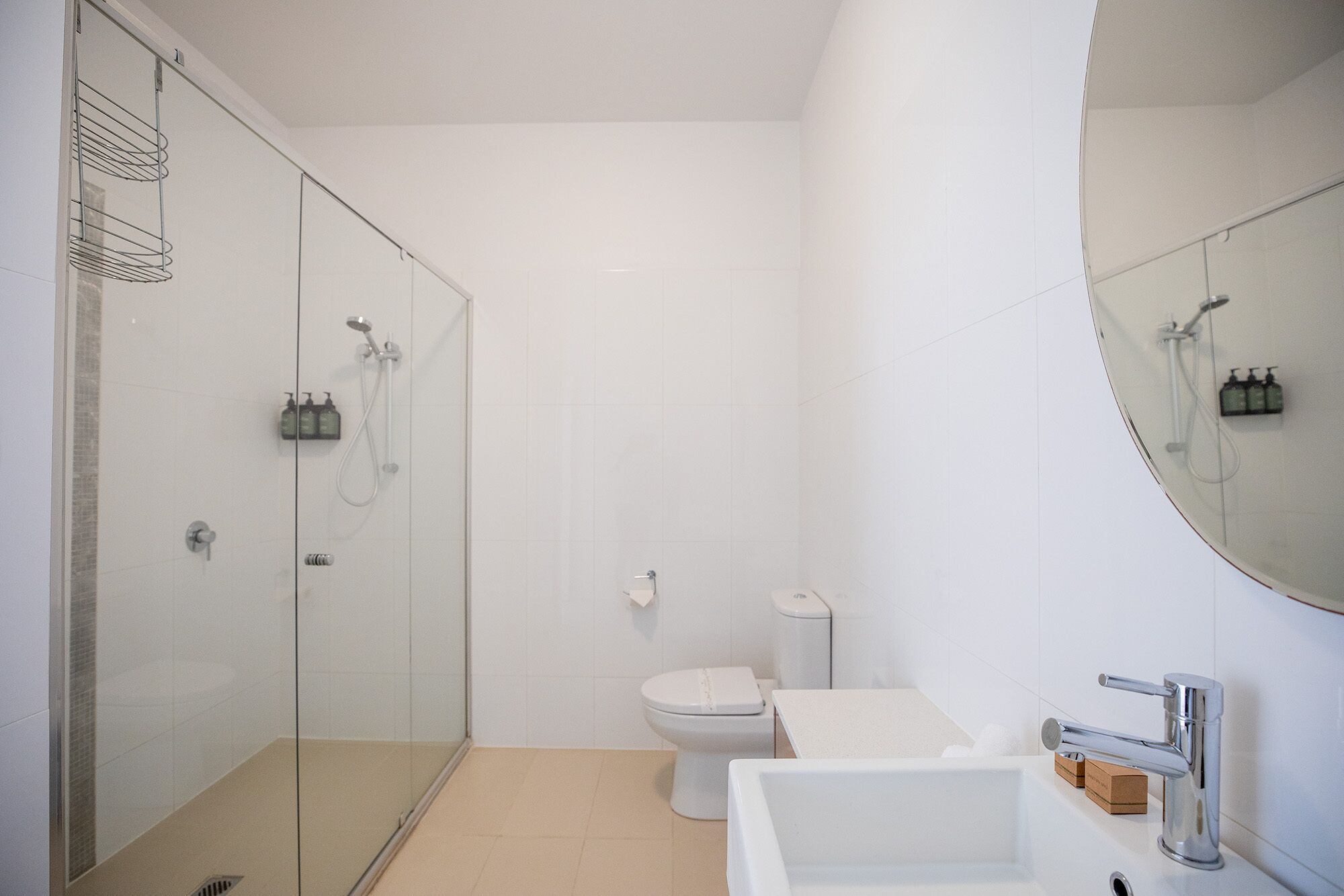 Un baño moderno con cabina de ducha de vidrio, inodoro, lavabo y un espejo grande.