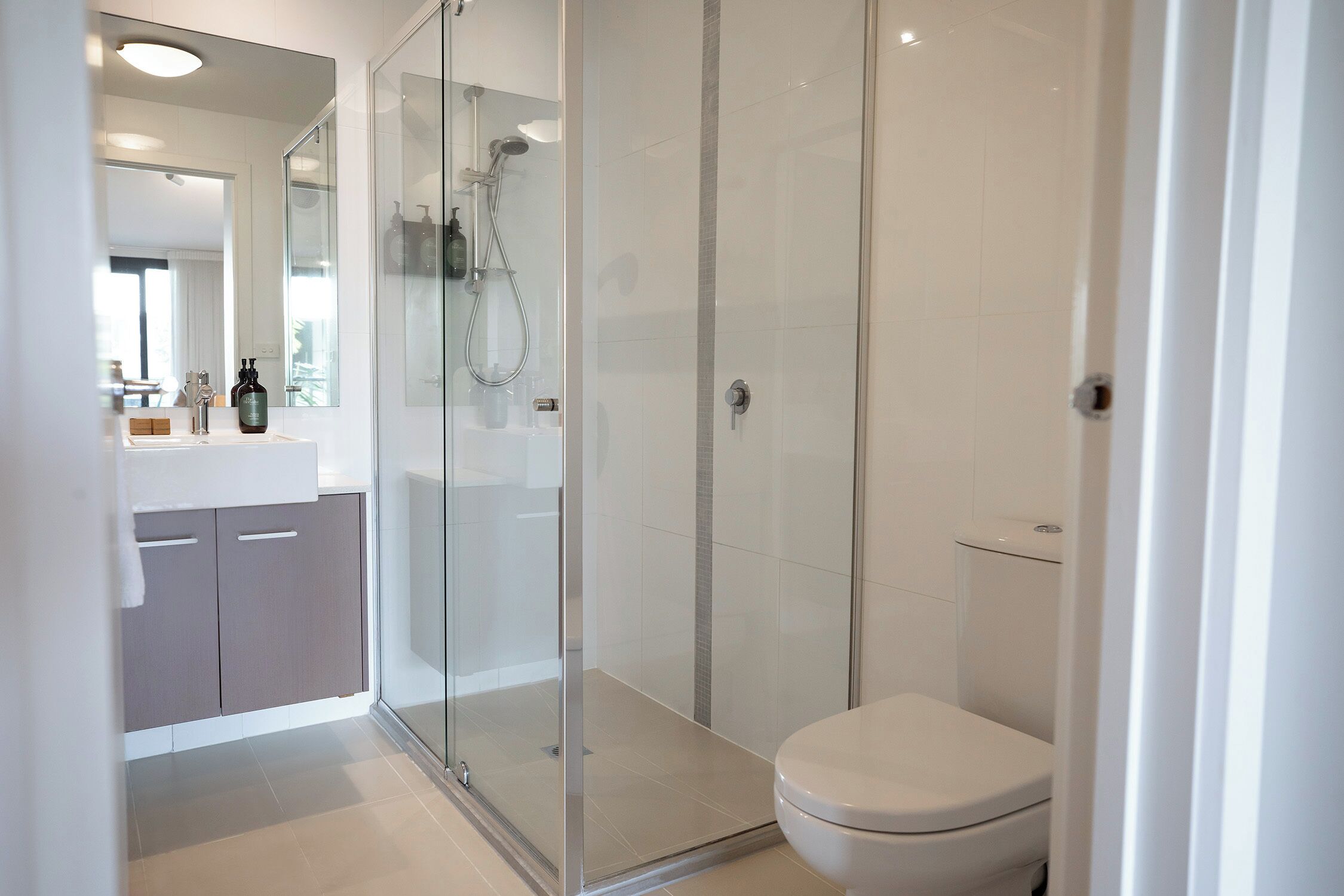 A modern bathroom with a glass shower enclosure, a toilet, and a vanity with a mirror.