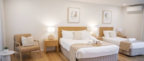 Une chambre d’hôtel avec deux lits, une chaise, une petite table et des œuvres d’art murales.