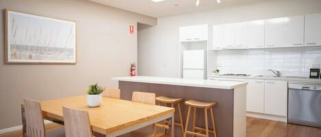 A modern kitchen with white cabinets, a wooden dining table, and a small island with stools.