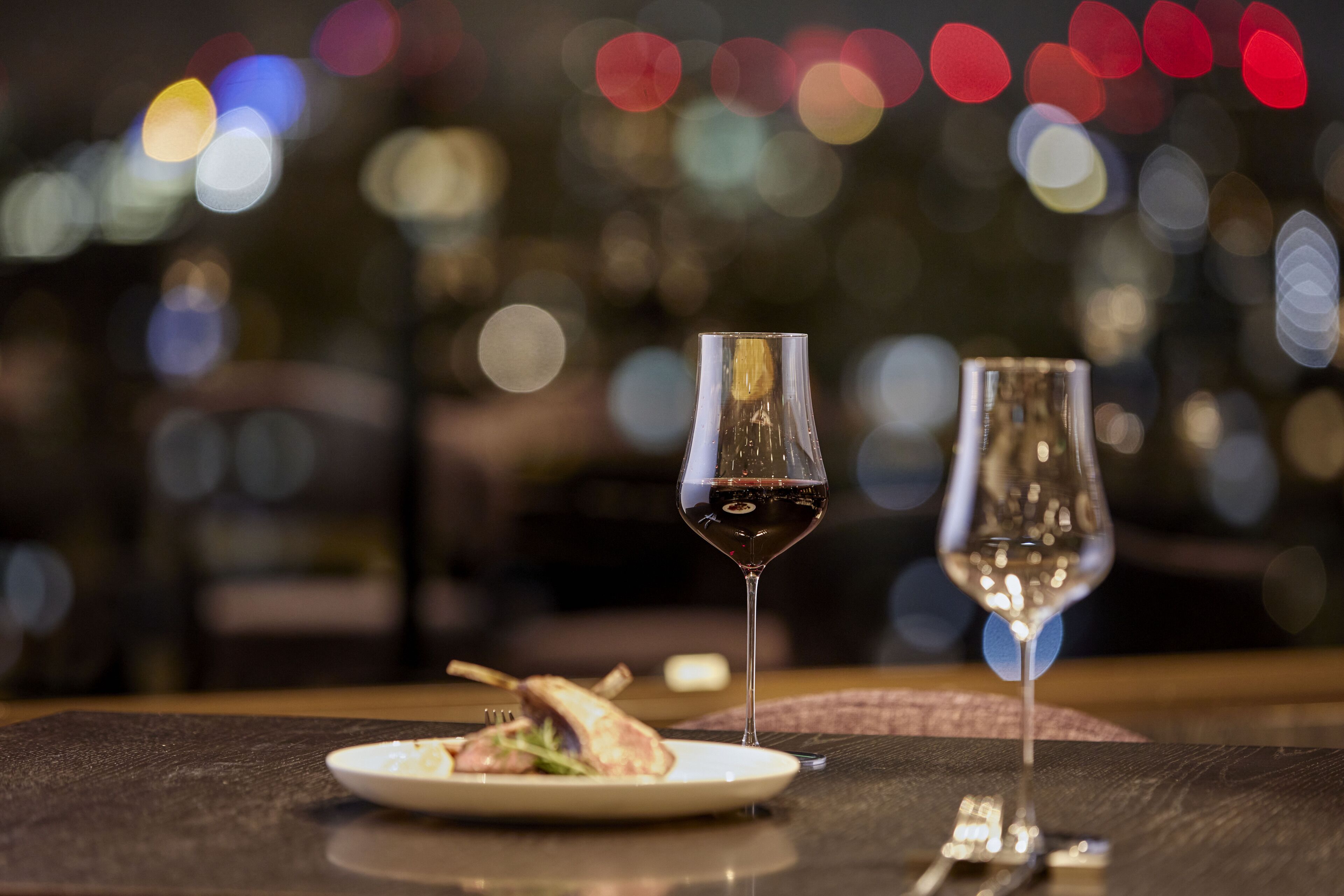 A dining table with a plate of food and two wine glasses.