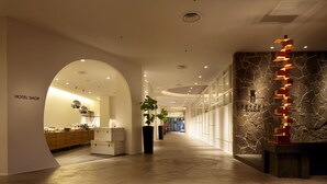 Un vestíbulo de hotel con diseño moderno, que incluye un mostrador de recepción, una escalera y una pared de piedra.