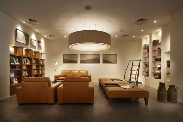 Un salon moderne avec des canapés en cuir, une table basse et des étagères remplies de livres et d’objets décoratifs.