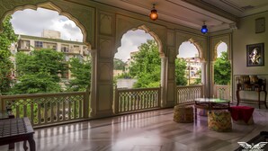 A room with a balcony, ornate arches, and a view of buildings and trees. - Krishna Palace - A Heritage Boutique Hotel (Jaipur)