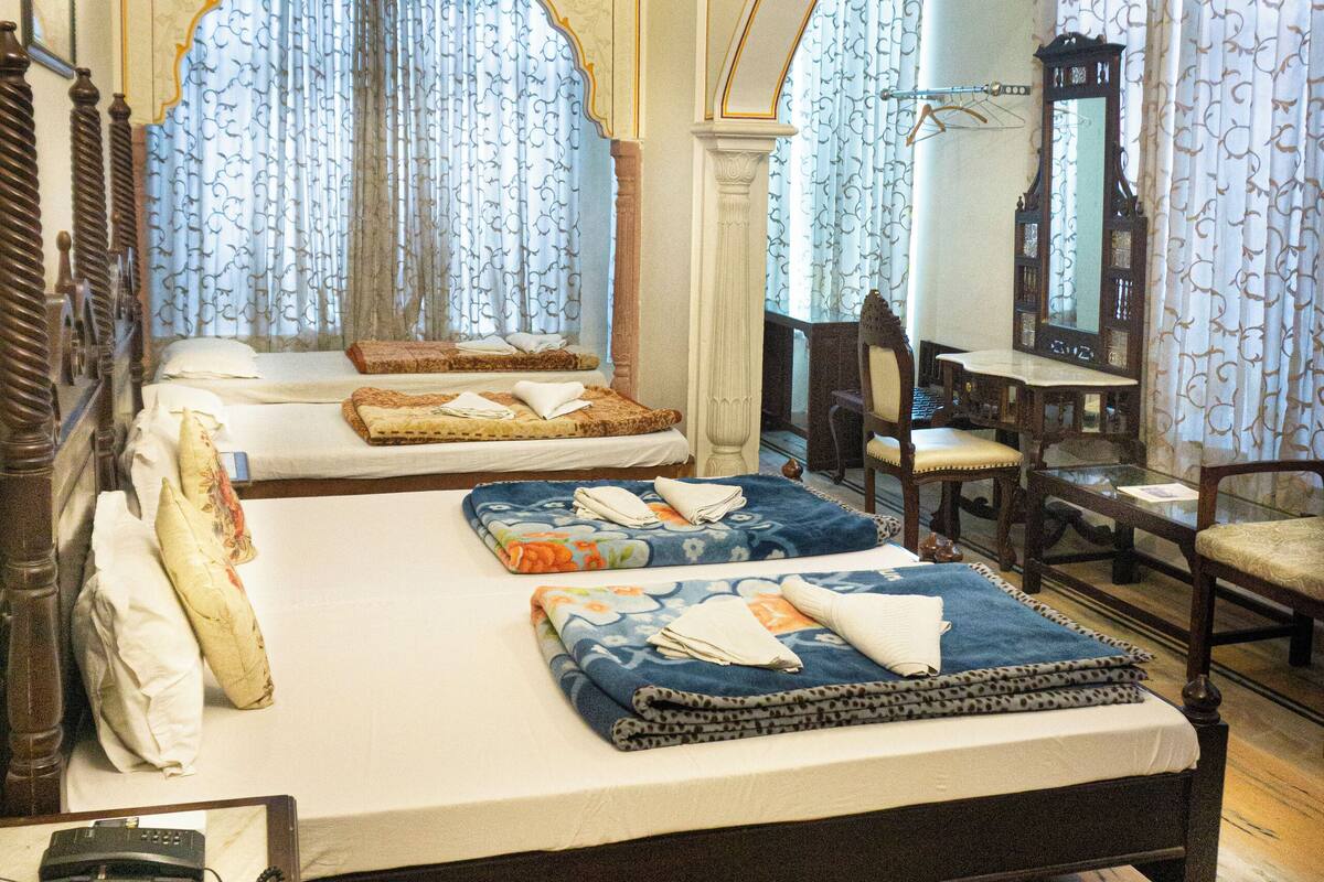 A bedroom with two beds, a ceiling fan, a mirror, and a desk with a chair.
